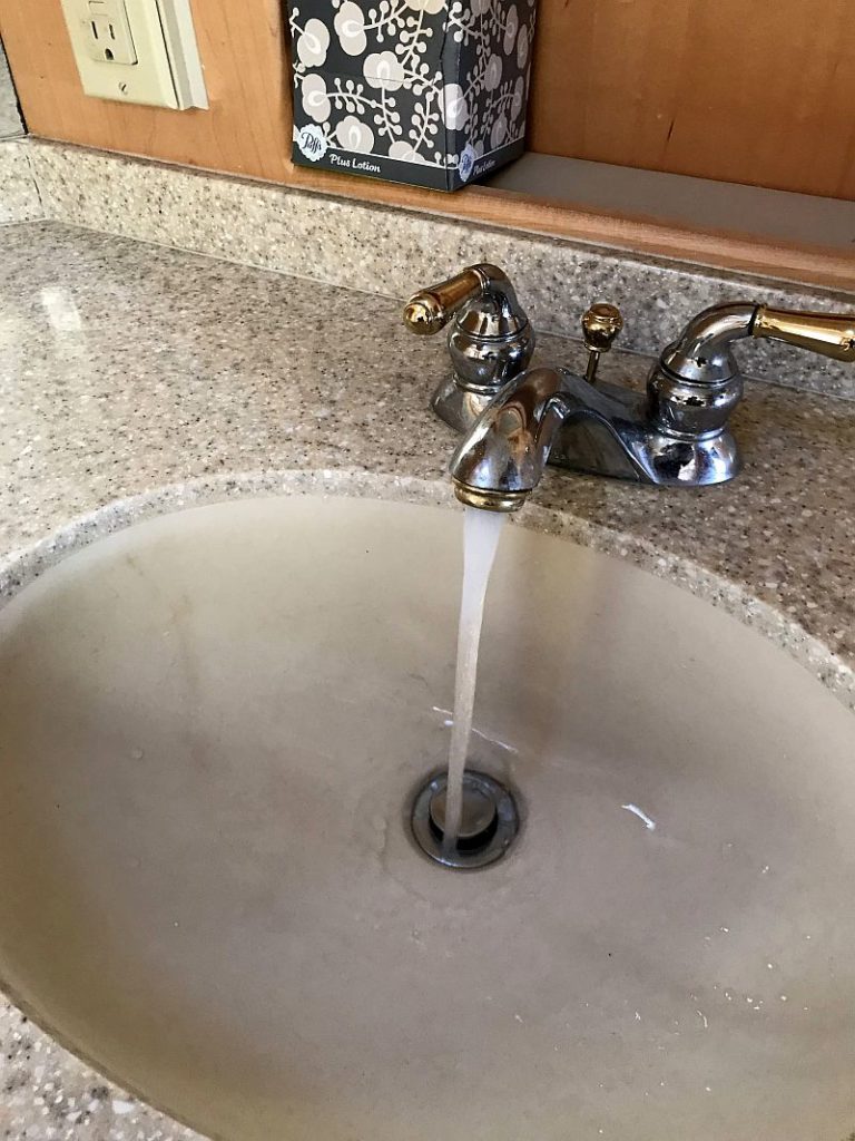 Picture of an RV Inspector checking the water pump via water flow